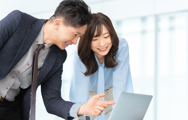 男女がパソコンを見ながら笑顔で話している