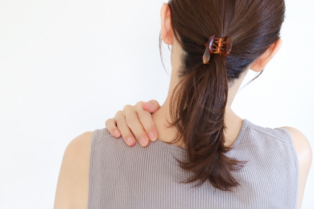 女性が肩に手を当てている