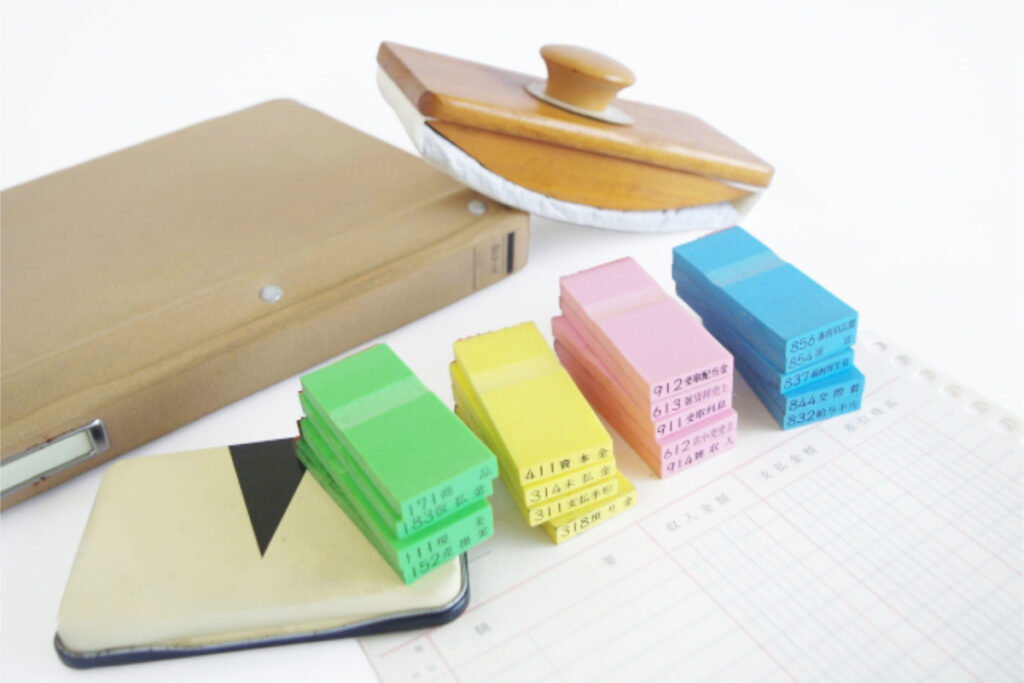 色分けされた帳票整理用のインデックス 帳簿 ファイル スタンプ台が並んでいる様子